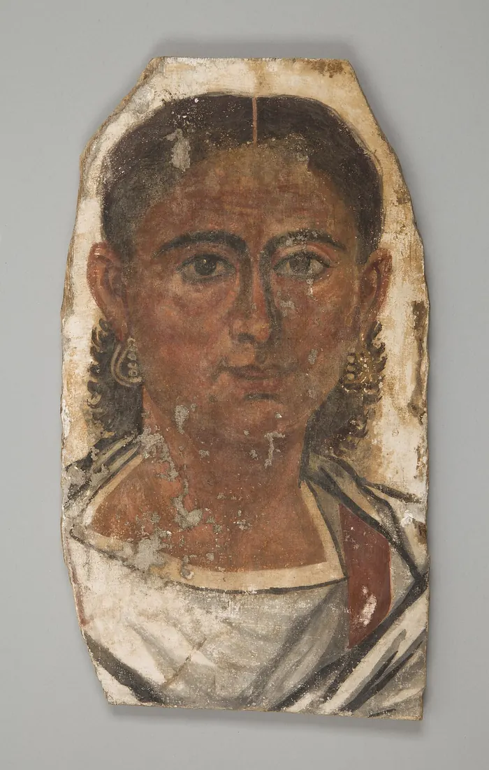 Painted mummy portrait of a young man with dark curls on a wooden panel